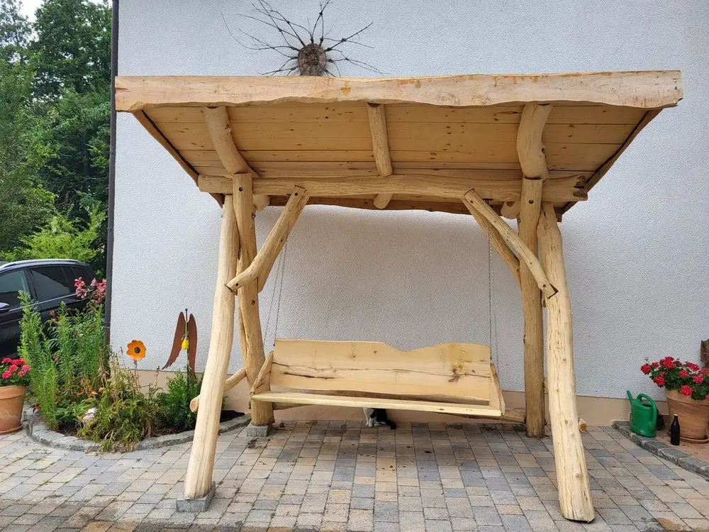 Überdachte Holzschaukel mit rustikalem Ständerwerk auf einem Hof