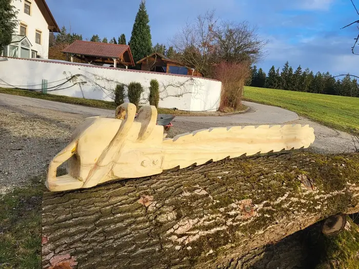 Überlebensgroße Motorsäge aus Holz auf einem Baumstamm